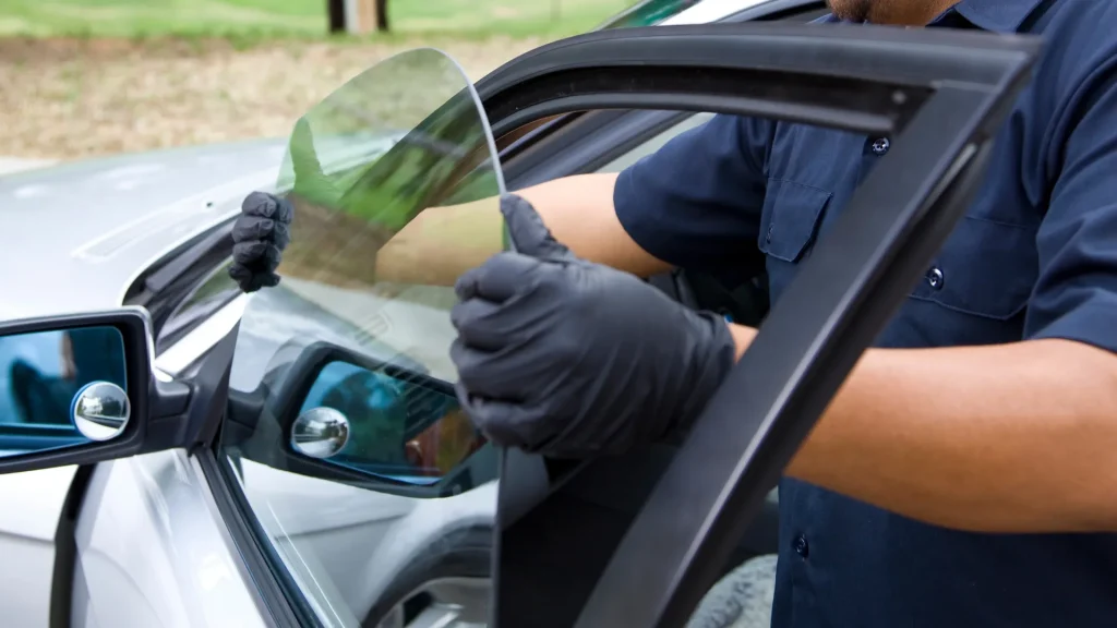 Auto glass technician in black gloves installing a new car window on a silver vehicle, Mobile Tech Auto Glass repair service